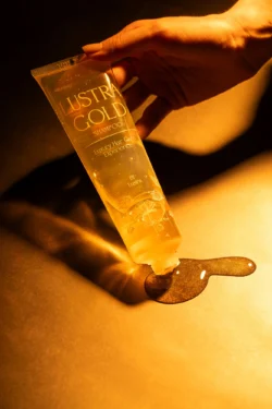 Sıcak sinematik ışıkta jel dökülen altın Lustra Gold şampuan tüpünün yüksek etkili ürün fotoğrafçılığı, fotoğrafçı Avrupa'da.