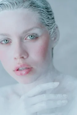 Soft-lit beauty portrait of a model with white body paint, frosted hair and glossy pink lips — polished beauty photography in Europe.
