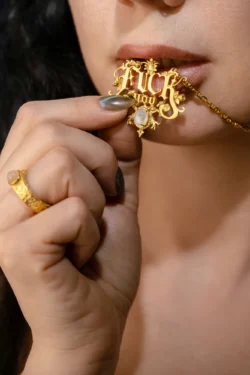 Avrupa'da bir fotoğrafçı tarafından çekilmiş cesur bir güzellik/editörlük fotoğrafında süslü bir altın kolyeyi ısıran bir kadının yakın çekimi.