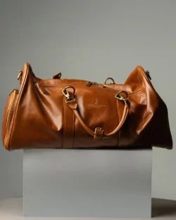 Sıcak vurgulara sahip bir kaide üzerindeki taba rengi deri spor çantasının cilalı stüdyo çekimi, Avrupa'daki projeler için ürün fotoğrafçılığı.