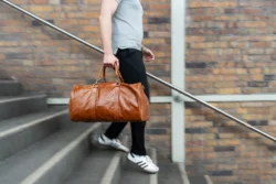 Avrupa'daki projeler için hareket bulanıklığı, dinamik ürün fotoğrafçılığı ile yerinde çekilmiş taba rengi deri bir spor çantası taşıyan merdivenlerden inen adam.