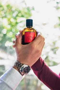 Ürün fotoğrafçılığı: sıcak arka ışık ve yumuşak bokeh ile elde tutulan kehribar parfüm şişesi; Avrupa'daki projeler için gösterişli reklam çekimi.