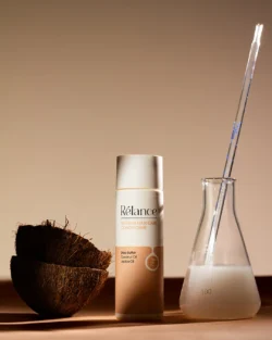 Polished studio-shot of Relance conditioner with halved coconut and beaker, beauty product photography for projects in Europe.