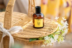 Beyaz çiçekli dokuma sepet üzerinde amber parfüm şişesinin sıcak sığ DOF ürün çekimi, Avrupa'da cilalı ürün fotoğrafçılığı.