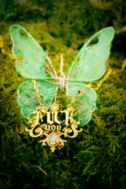 Yeşil yarı saydam kanatlı yosun üzerinde altın bir fuck you kolyenin cilalı stüdyo çekimi; Avrupa için ürün fotoğrafçılığı.