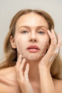 Köpüklü temizleyici uygulayan bir kadının yakın plan güzellik portresi; Avrupa'daki projeler için bir fotoğrafçı tarafından stüdyoda çekilmiş cilalı güzellik fotoğrafçılığı.