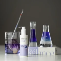 Ürün fotoğrafçılığı için mor laboratuvar cam malzemeleriyle Rélance el ve vücut losyonunun cilalı stüdyo çekimi; Avrupa'da ticari fotoğrafçı.