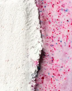 Pembe benekli bir yüzeyle buluşan beyaz tozun makro stüdyo çekimi, net aydınlatma, Avrupa'daki projeler için yüksek etkili ürün fotoğrafçılığı.