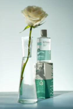 Cam vazoda beyaz bir gülün yanında Rélance misel suyunun cilalı ürün fotoğrafı, minimalist stüdyo çekimi, Berlin & Avrupa