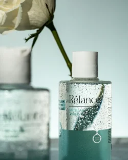 Beyaz bir gülün yanında su boncuklu misel su şişesinin cilalı stüdyo çekimi güzellik ürünü - Avrupa'daki projeler için ürün fotoğrafçılığı