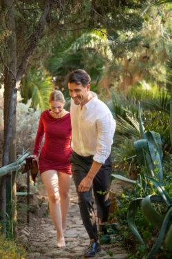 Güneşli bir bahçe yolunda yalınayak yürüyen gülümseyen bir çiftin sinematik editoryal çekimi, sıcak doğal ışık - Avrupa'da fotoğrafçı