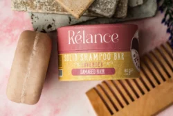 Avrupa'daki müşteriler için ürün fotoğrafçılığı, pastel fonda lavanta rengi katı bir şampuan çubuğu ve ahşap tarağın cilalı stüdyo çekimi.