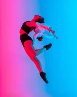 Neon pembe ve camgöbeği stüdyo ışığında havada sıçrayan dinamik dansçı portresi, cilalı ticari stil - Avrupa için Berlin merkezli fotoğrafçı.