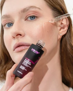 Bir serum damlalığı berrak yağ salgılarken modelin nemli yanağının yakın plan güzellik çekimi, Avrupa çapında cilalı stüdyo ürün fotoğrafçılığı.