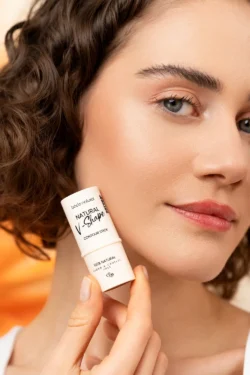 Yanağında kontür çubuğu tutan bir modelin cilalı yakın çekimi, yumuşak stüdyo aydınlatması, Berlin'de ürün fotoğrafçılığı.