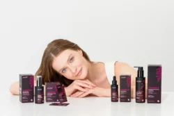 Bordo Viniferine cilt bakım şişeleri arasında uzanmış bir modelin stüdyo çekimi güzellik ve ürün fotoğrafçılığı, fotoğrafçı Avrupa'da.