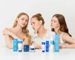 Mavi cilt bakım tüpleri ve kavanozlarının arkasında bir stüdyoda üç model; Avrupa'daki projeler için cilalı güzellik ürünü fotoğrafçılığı.