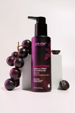 Mat siyah Viniferine pompa şişesi, soluk bir fonda koyu üzümlerle stilize edilmiş, Avrupa için yüksek etkili ürün ve güzellik fotoğrafçılığı.