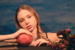 Narın üzerinde dinlenen örgülü genç bir kadının sinematik sanatçı portresi, yumuşak stüdyo aydınlatması ve karamsar tonlar - Berlin'de fotoğrafçı.