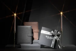 İki deri planlayıcının ve yanan mumlarla çevrili kurdeleli markalı bir hediye kutusunun cilalı ürün fotoğrafı - Avrupa için fotoğrafçı.