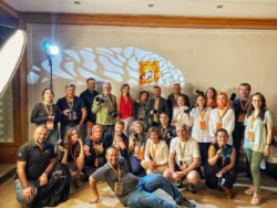 Fotografen posieren in einem warm beleuchteten Seminarraum mit Kameras und Gobo-Licht - praktischer Fotografie-Workshop in Berlin.