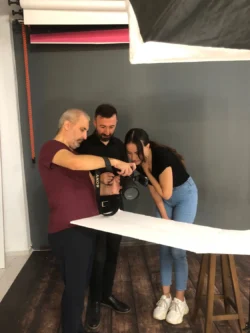 Ein Kursleiter demonstriert zwei Schülern die Kameraeinstellungen in einer praktischen Studio-Einzelschulung in Berlin.