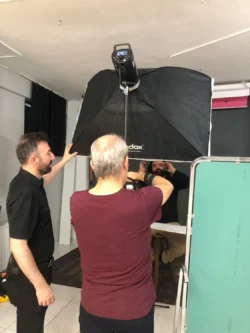 Der Fotograf dirigiert einen sitzenden Kunden bei einem Studio-Shooting für ein ausgefeiltes Business-Headshot, ein praktisches Werbeshooting in Berlin.