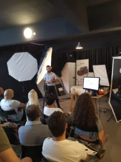 Ein Kursleiter demonstriert den Teilnehmern eines praktischen Fotografie-Workshops in Berlin Kamera und Studiobeleuchtung.