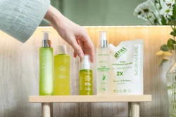 Yeşil biberiye cilt bakımı şişelerinin ve pompayı tutan bir elin stüdyo yakın çekimi; Avrupa'daki projeler için cilalı ürün fotoğrafçılığı.