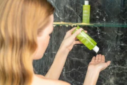 Cilalı, yerinde duş sahnesinde biberiye şampuanı döken bir kadının yakın çekimi - Avrupa'daki projeler için ürün fotoğrafçılığı.