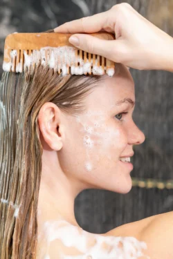 Şampuanlı saçlarını köpükle tarayan gülümseyen bir kadının yakın çekimi, Berlin'deki fotoğrafçı tarafından güzellik fotoğrafçılığı ve kampanya çekimi.