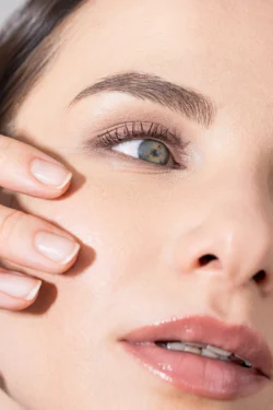 Cilalı güzellik fotoğrafçılığı, bir kadının gözüne yakın çekim, bakımlı kaş, uzun kirpikler ve parlak dudaklar; fotoğrafçı Avrupa'da.