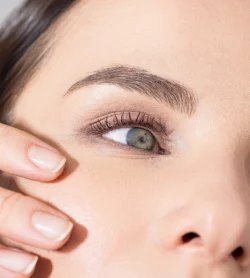 Bir modelin yeşil gözünün ve manikürlü elinin cilalı yakın çekim güzellik fotoğrafı, stüdyo aydınlatması - Avrupa'daki projeler için güzellik fotoğrafçılığı.